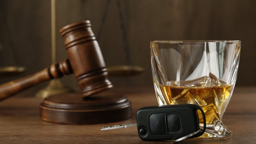 DUI Lawyer concept featuring a judge’s gavel, a glass of whiskey, and car keys, highlighting the importance of a skilled DUI Lawyer for legal defense after a drunk driving charge.