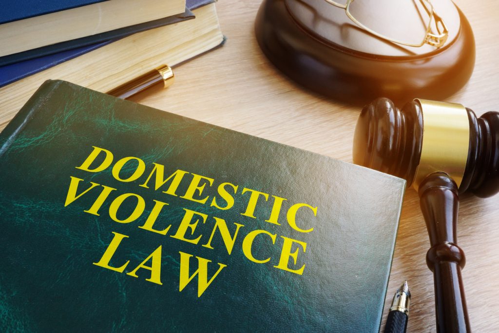 Domestic assault law book with a judge’s gavel and legal documents on a wooden desk.
